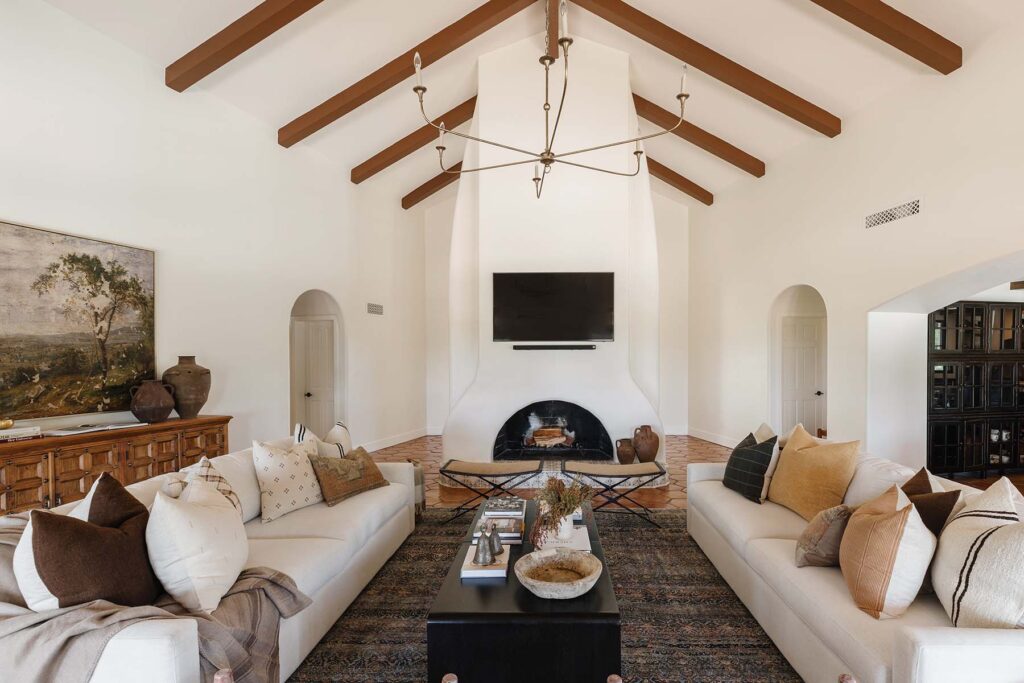 A Spanish Colonial style Mediterranean house with terracotta flooring, exposed wood beams, White plaster walls, low White linen seatings, rugs and rough iron details…